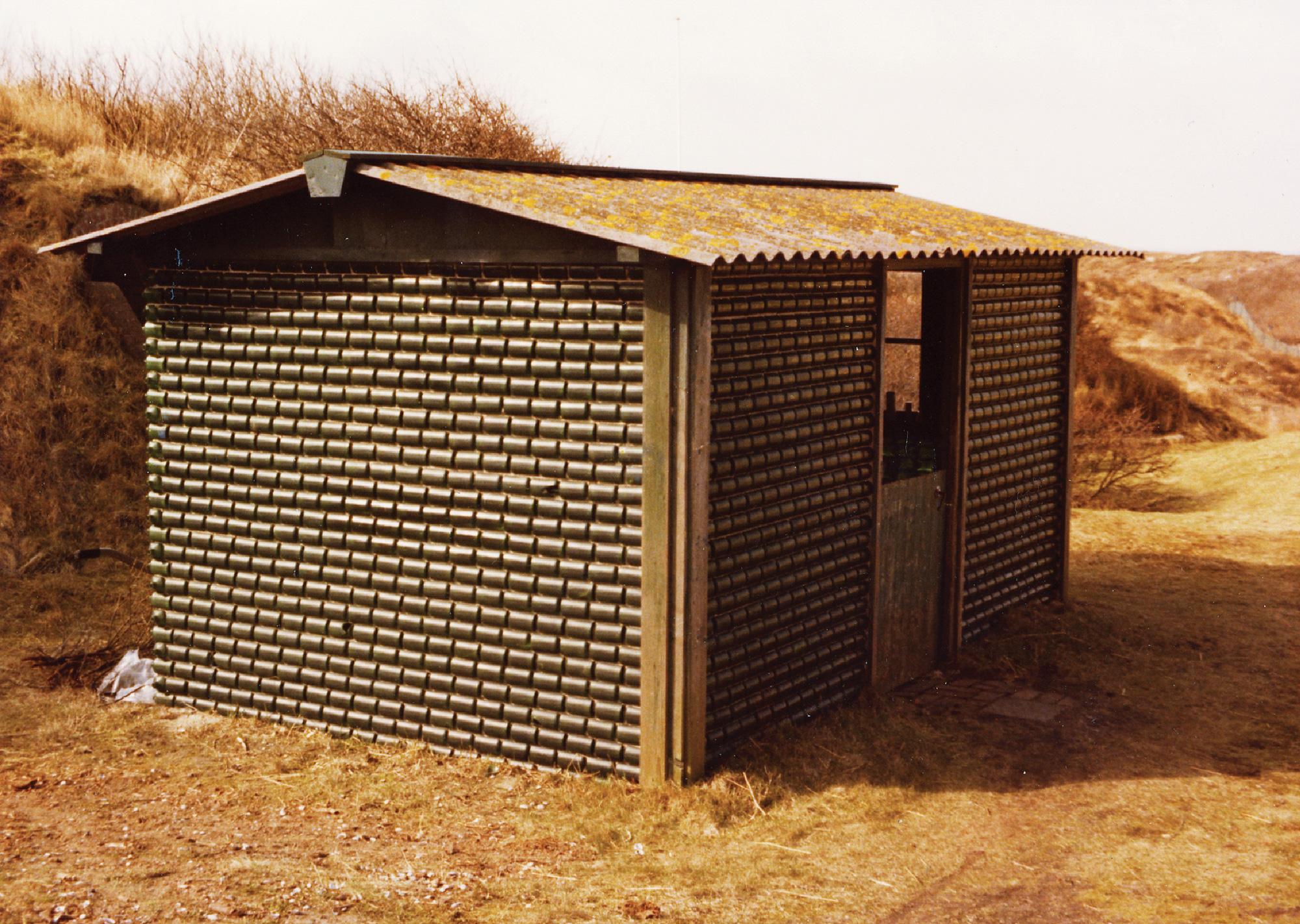 A photograph of a small house made out of WOBOS (World Bottles), built in 1965 near Alfred Heineken’s villa in Noordwijk, Holland.