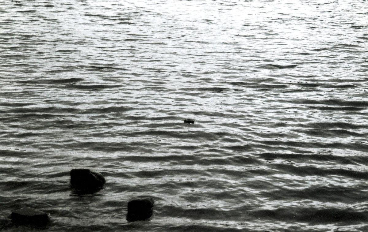 A photograph of a small paper coffin floating on the River Thames.