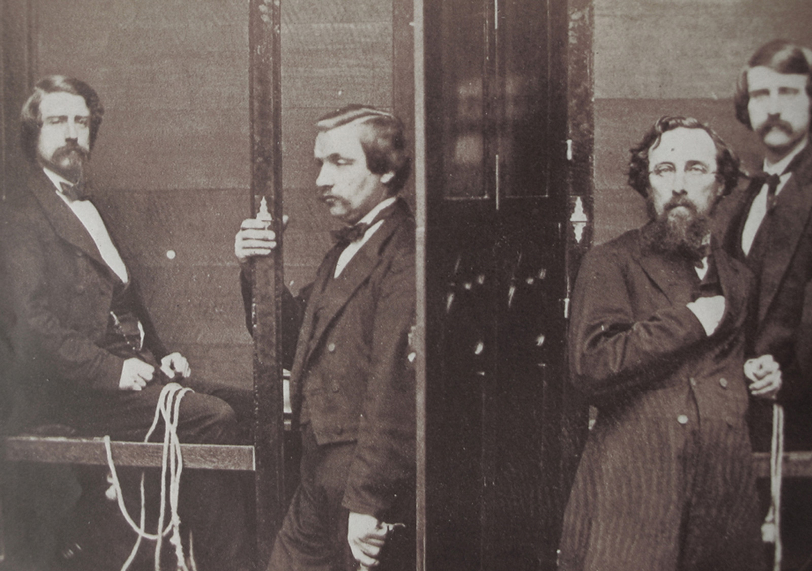 A photograph of the Davenport Brothers inside their spirit cabinet. From left: Ira Davenport, William Fay (their manager), author Robert Cooper, and William Henry Davenport. 