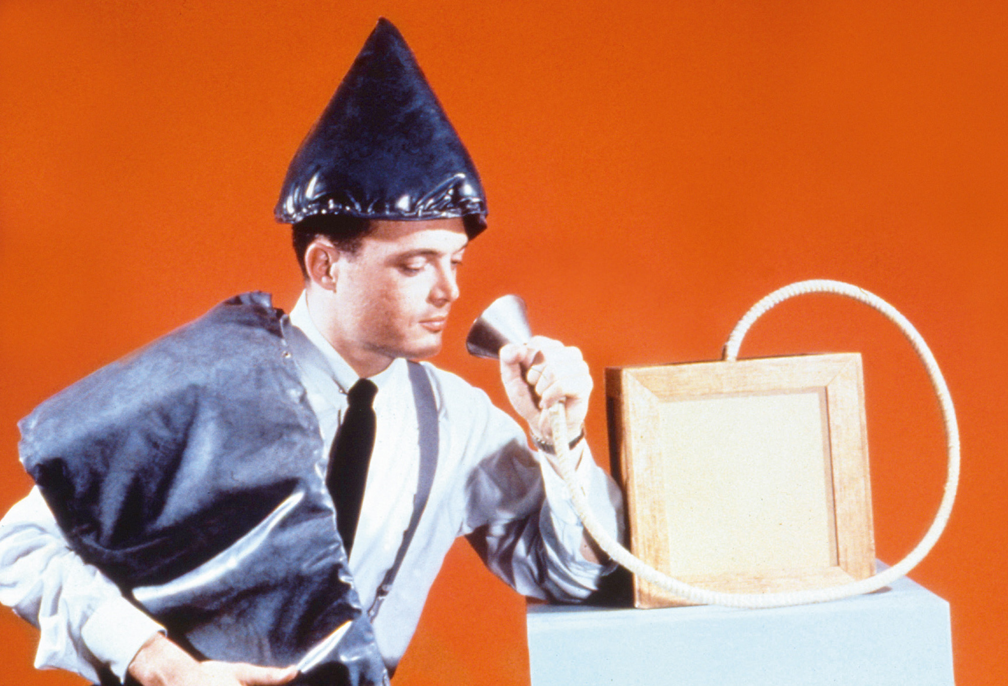 A nineteen fifty-six Food and Drug Administration official holding the funnel of an “orgone shooter” used for directing orgone rays at localized wounds and infections, and modeling an orgone blanket and hat intended for bed-bound patients.