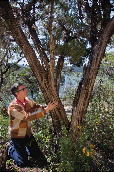 A photograph of the author kneeling and holding a tree. 