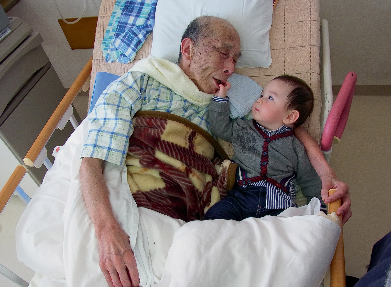 The front of the postcard from this issue. It is a photograph of an elderly, possibly dead, man holding a child in his arms. 