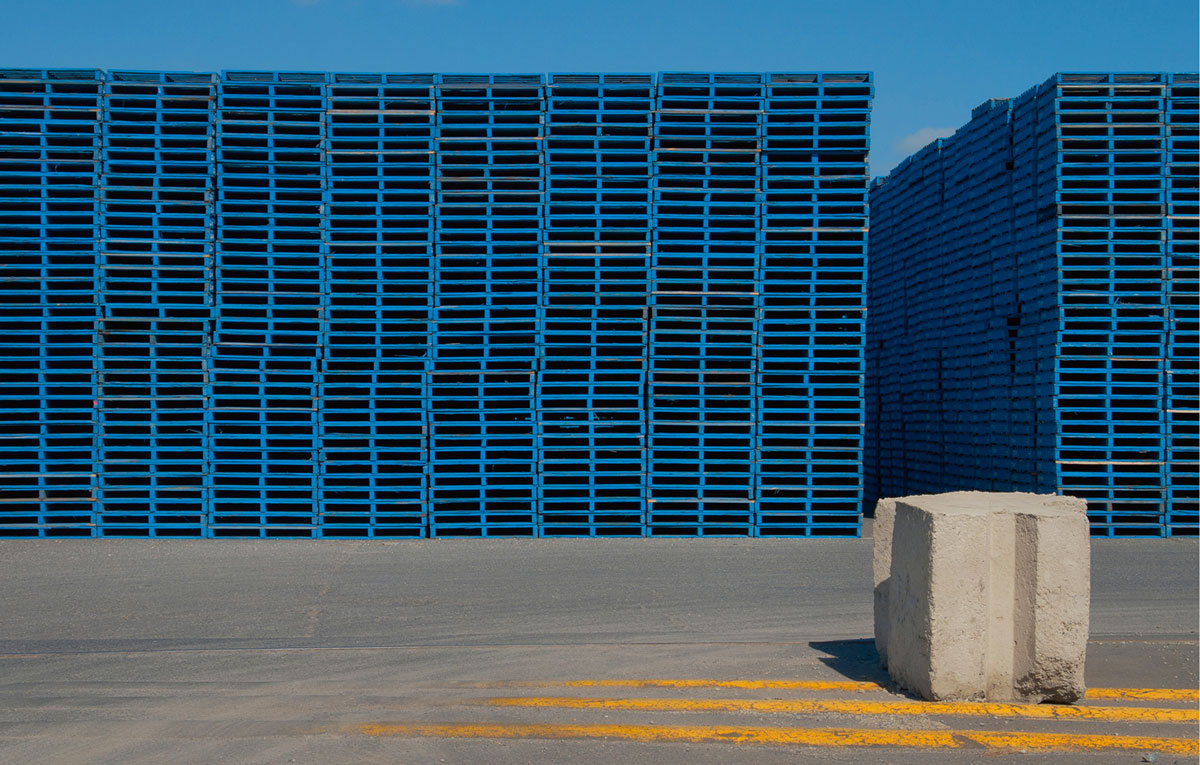 A photograph of piles of wooden shipping pallets at the CHEP depot at Port Adelaide, Australia. 