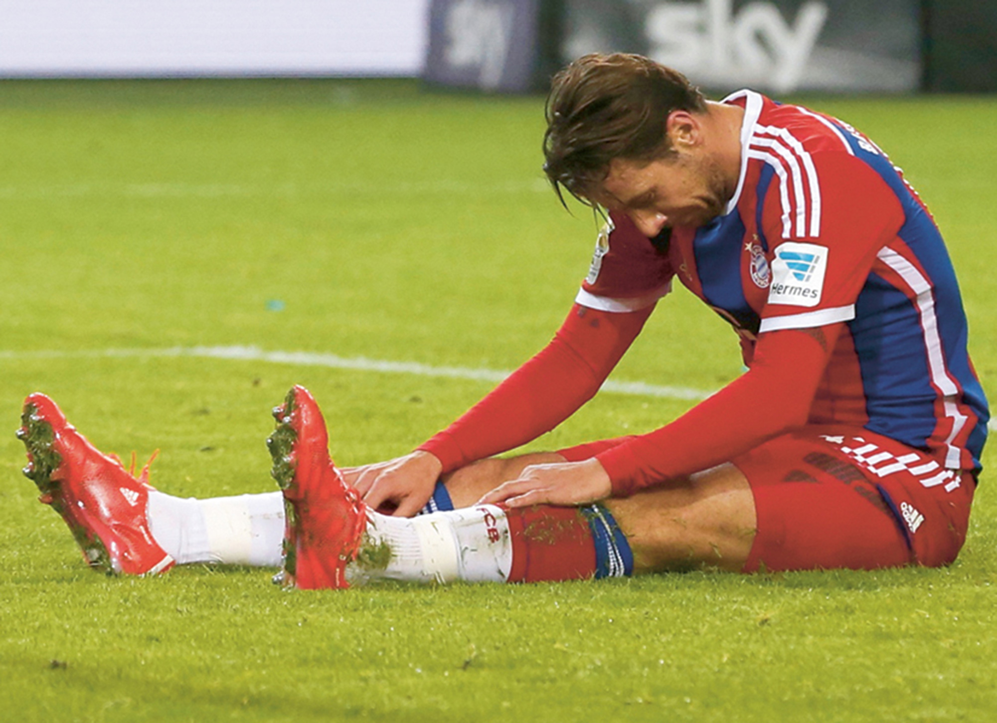 A photograph of a dejected soccer player sitting slumped over on the pitch.