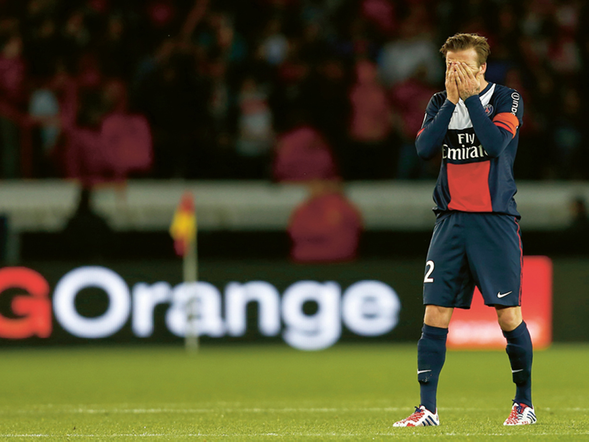 A photograph of soccer David Beckham player covering his face with his hands.